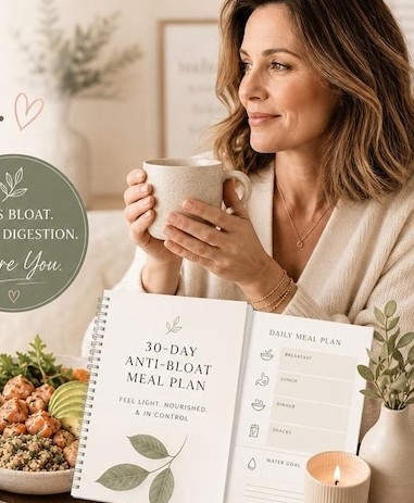 A woman holding a cup of tea beside the printed 30-Day Anti-Bloat Meal Plan and a daily meal page